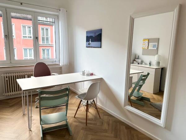 Interior view of therapy room 1 with a view of the desk, chairs, window in the background, mirror and reflection of a closet system