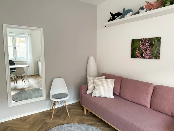 Interior view of therapy room 3 with a view of a corner with a couch, stuffed animals, mirror and reflection of a desk with a window in the background